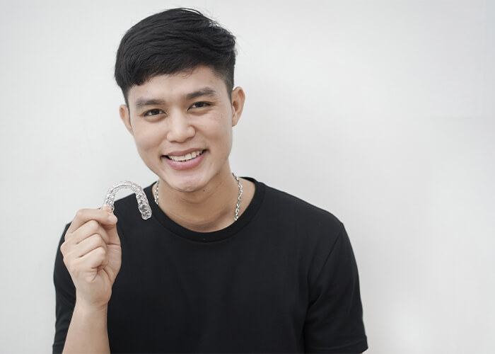 A young man holding his Invisalign clear aligners