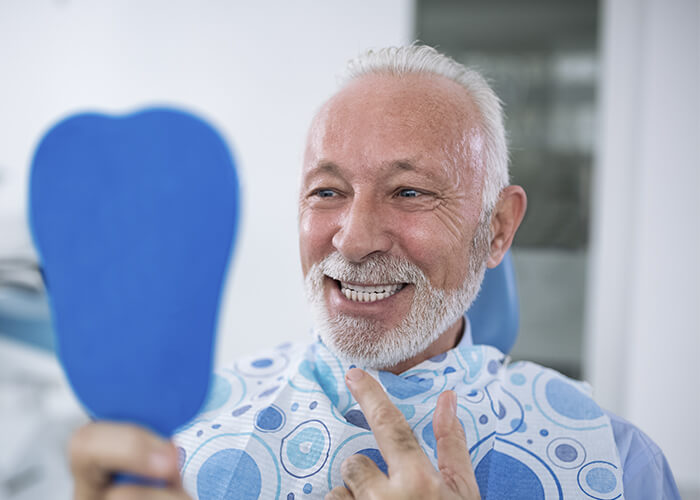 An older man checking his smile in a mirror